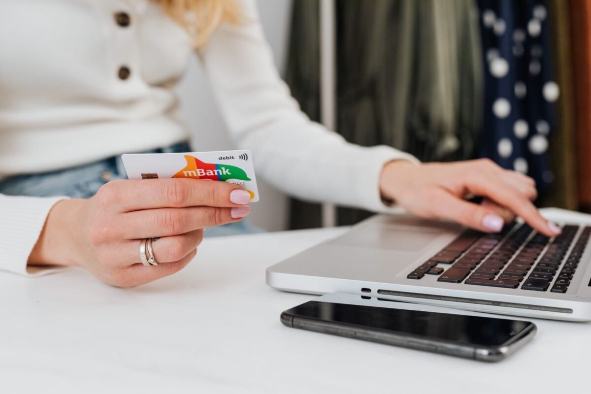 Person using laptop while holding a credit card