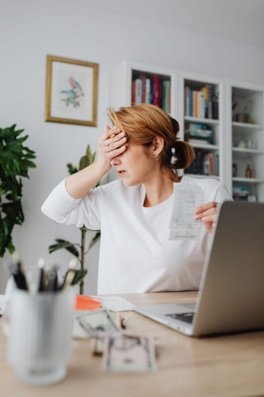 Woman holding a receipt at laptop