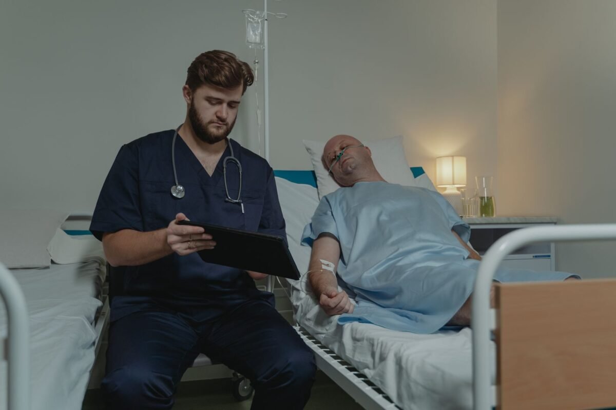 Doctor sitting beside man on hospital bed