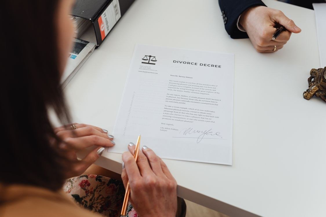 Close-up of two people signing documents at a law office table.