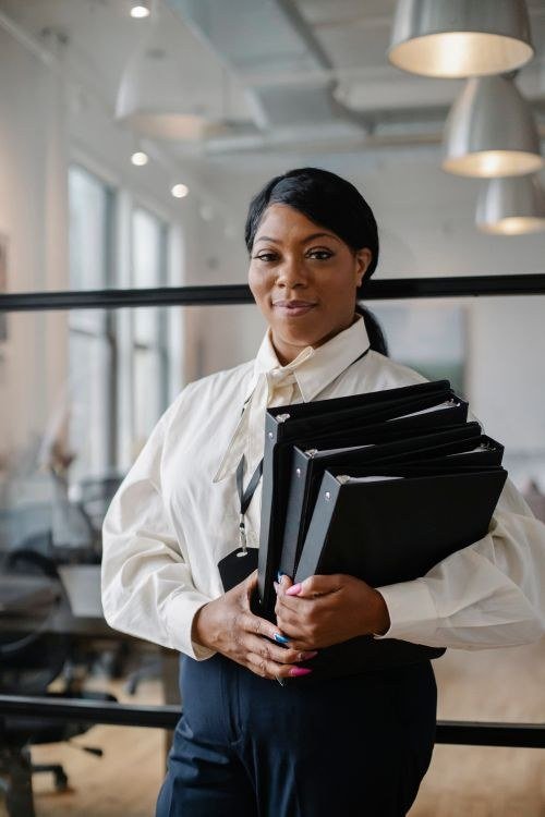 Positive black woman carrying documents in folders.
