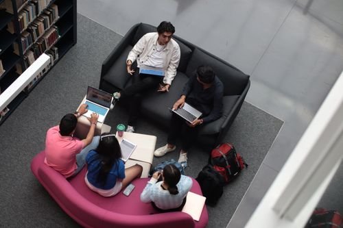 Diverse students studying with laptops in a library — illustrating investment incentives for disadvantaged-area private schools