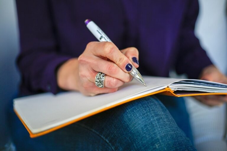 A woman writing a plan in a notebook with a pen