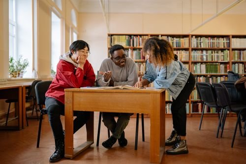 Students collaborating with a laptop in a library — illustrating vocational and skills certificates' legal value