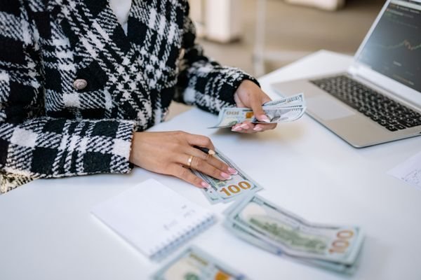 Person counting cash on a table (illustrative)